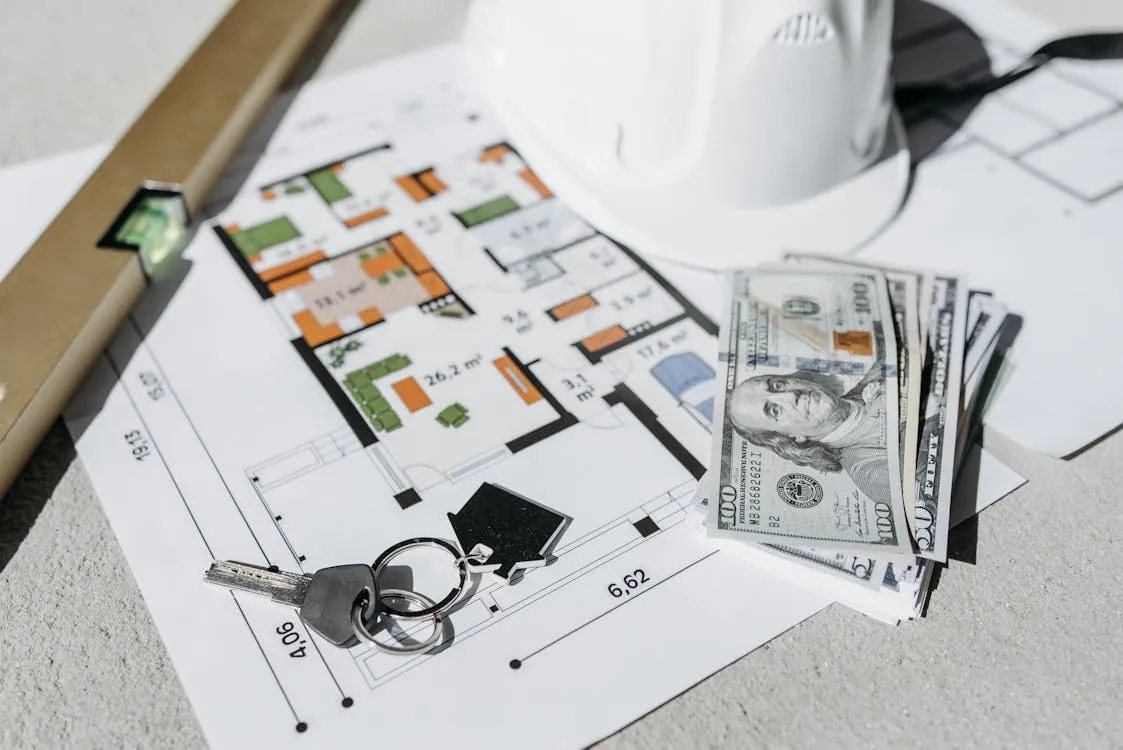 House keys on a floor plan with cash and a hard hat — symbolic of a Davao lease signing and the money on the line